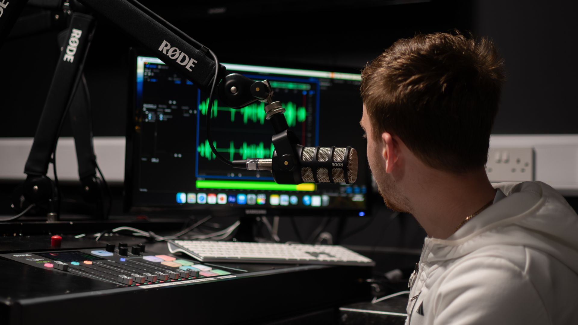 Male student in recording studio looking at computer screen.