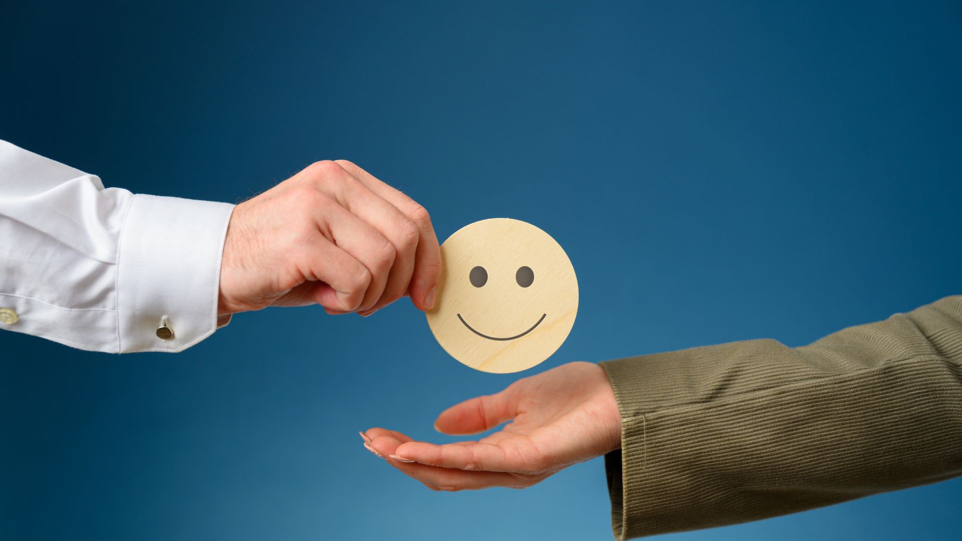 Person handing another person a wooden smiling face