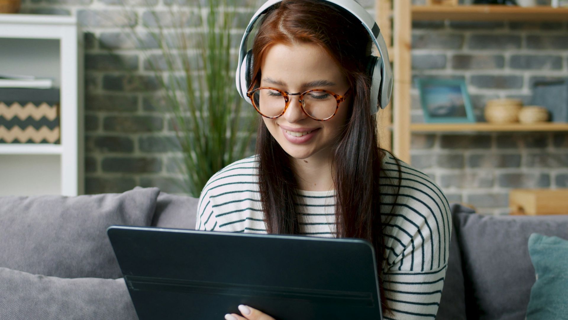 Young woman wearing headphones smiling down at tablet
