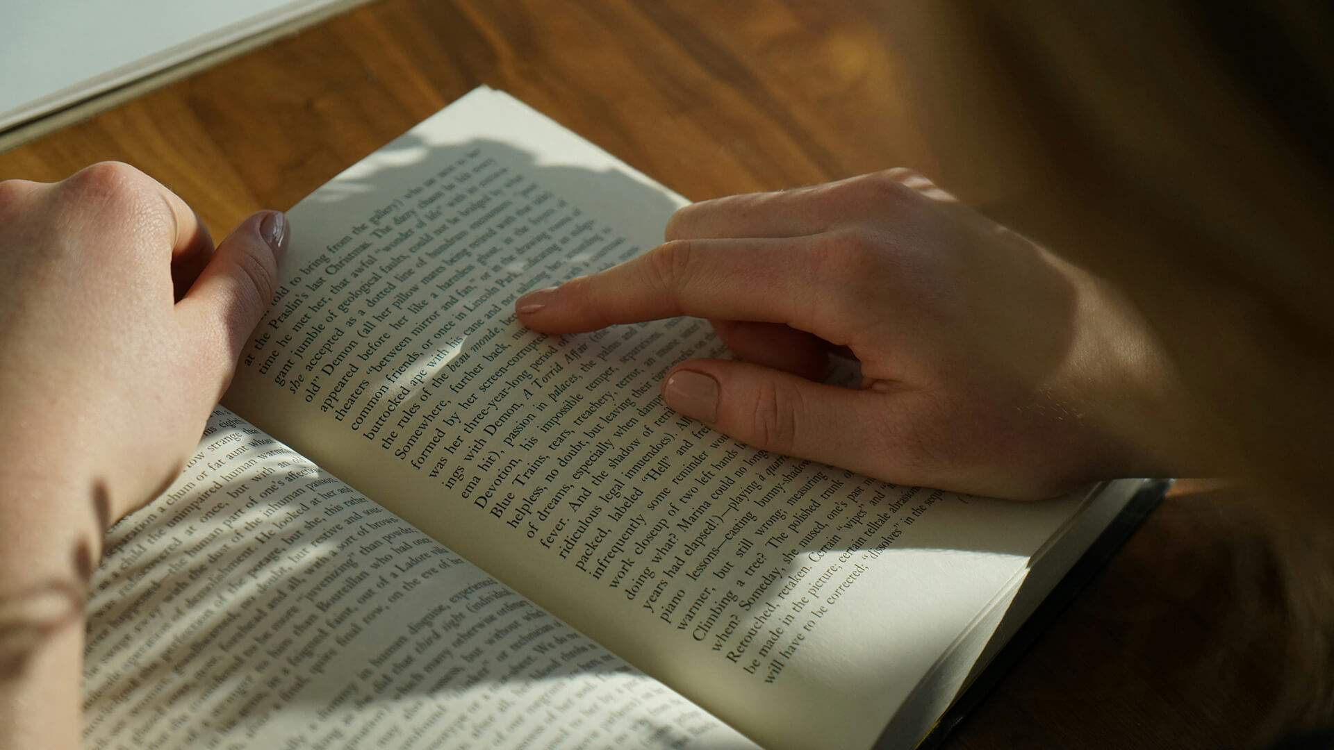 Young woman in a library reading a textbook and smiling.