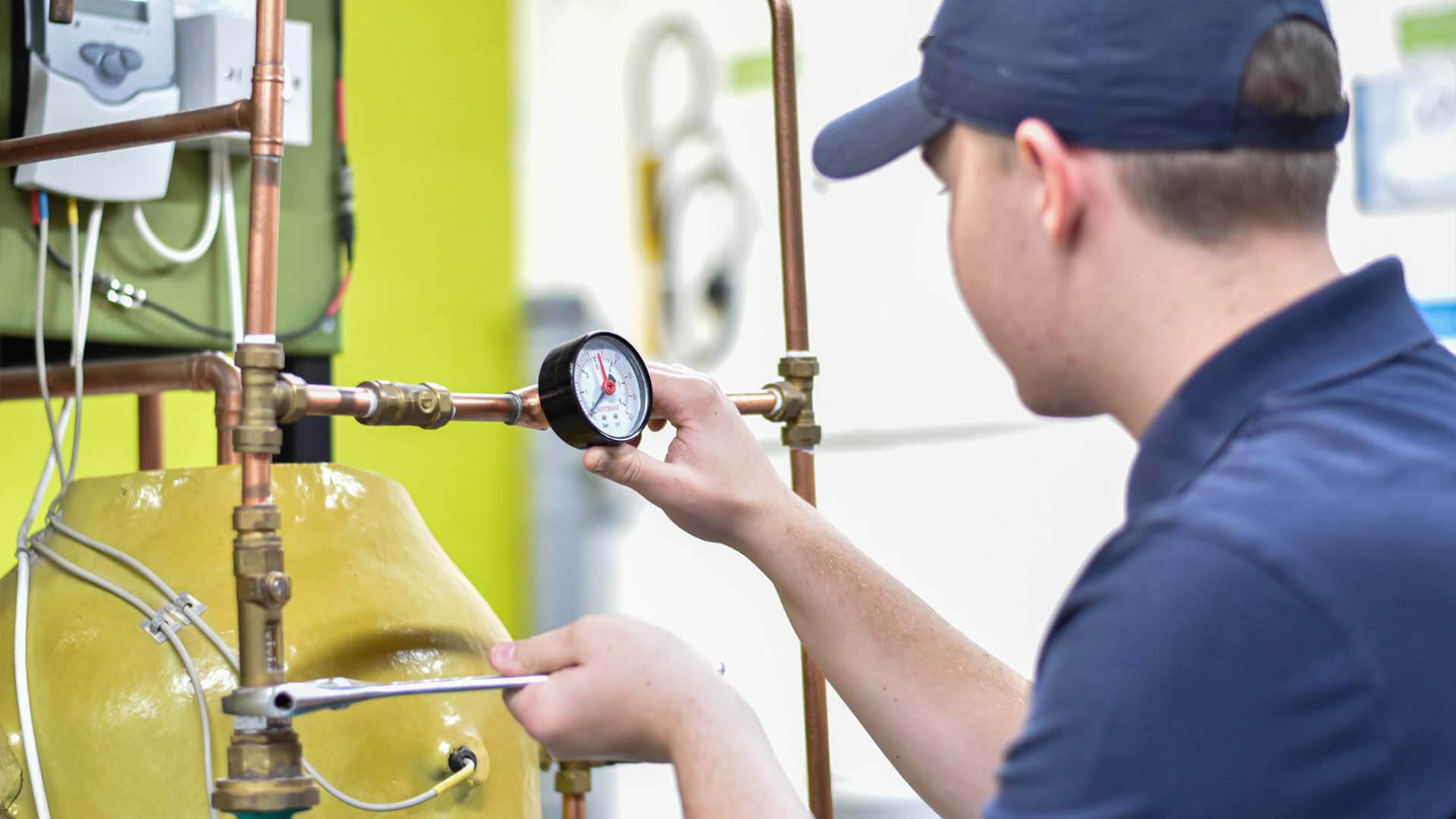 Young woman wearing a cap, working on pipes and checking the pressure.