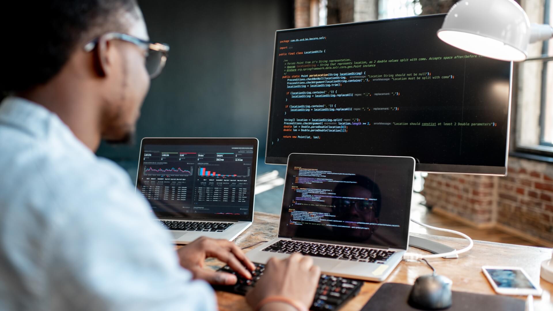 Man sat at desk with computer programs open.