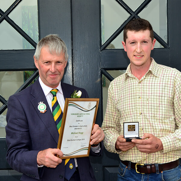 Two men standing with a certificate and agriculture award and smiling.