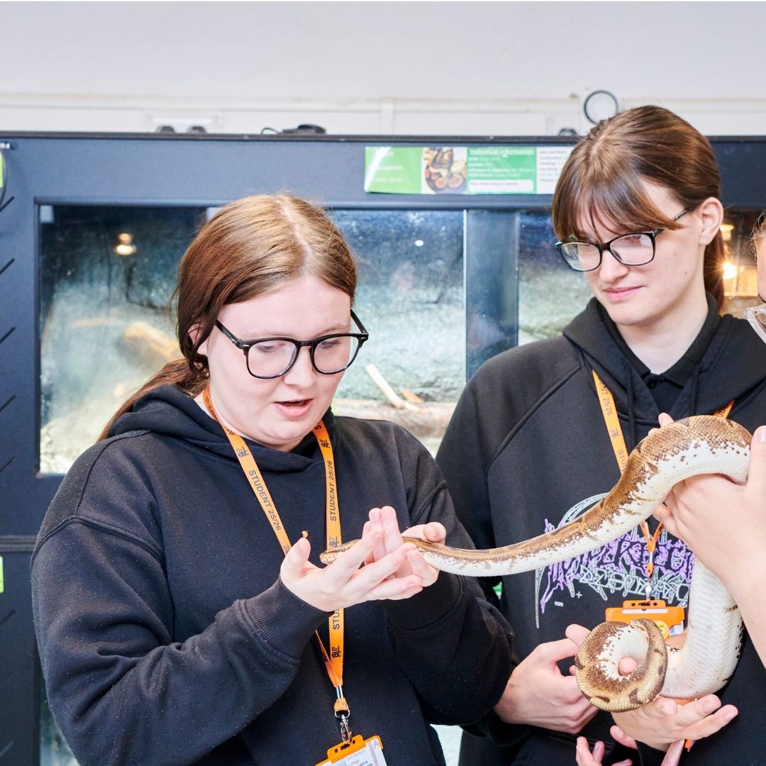 Two students holding large snake.
