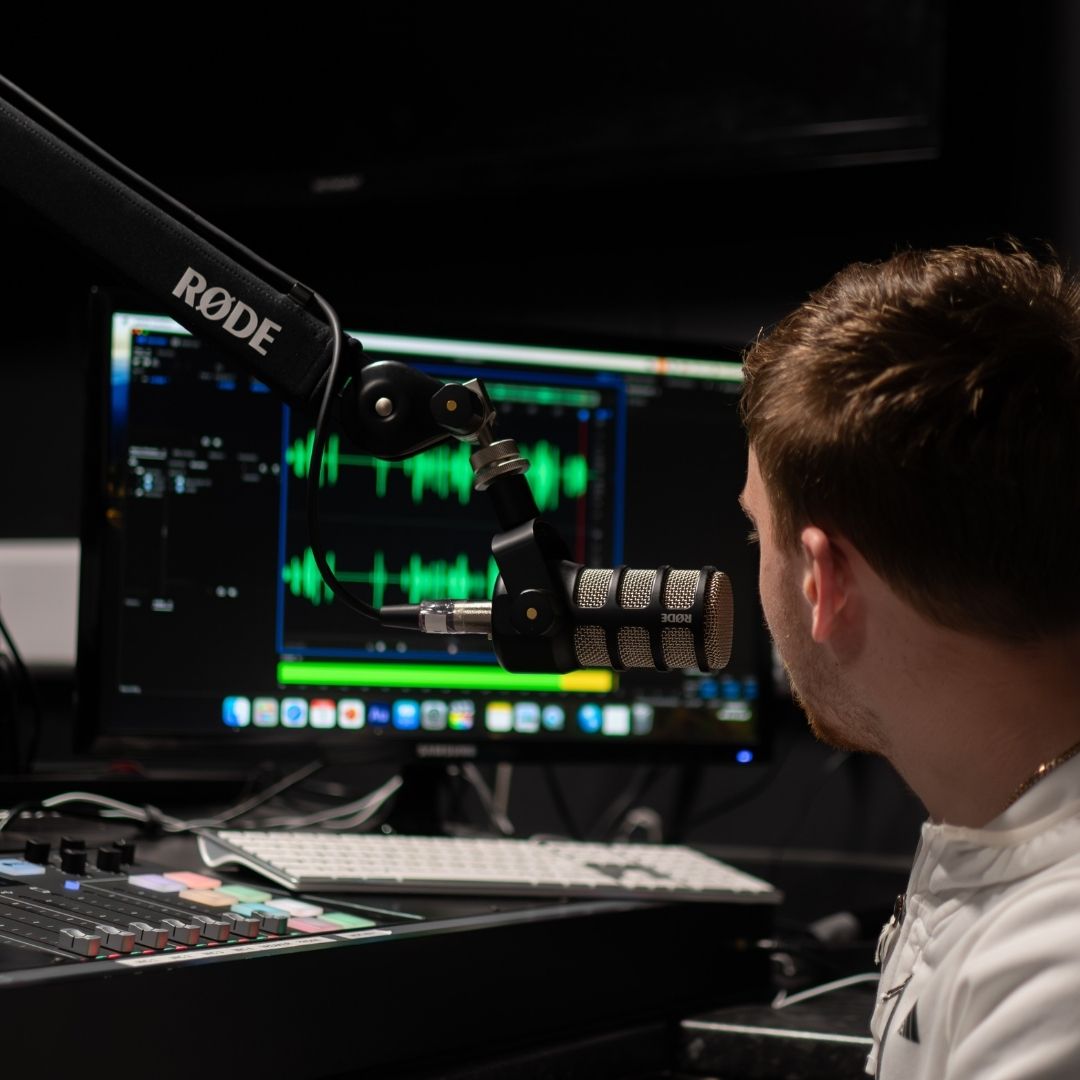 Male student in recording studio looking at computer screen.