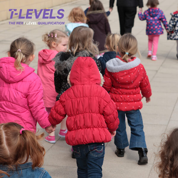 Various children in coats walking in a line outside