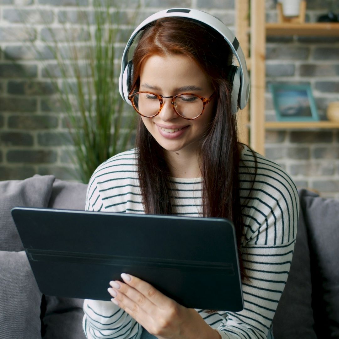 Young woman wearing headphones smiling down at tablet
