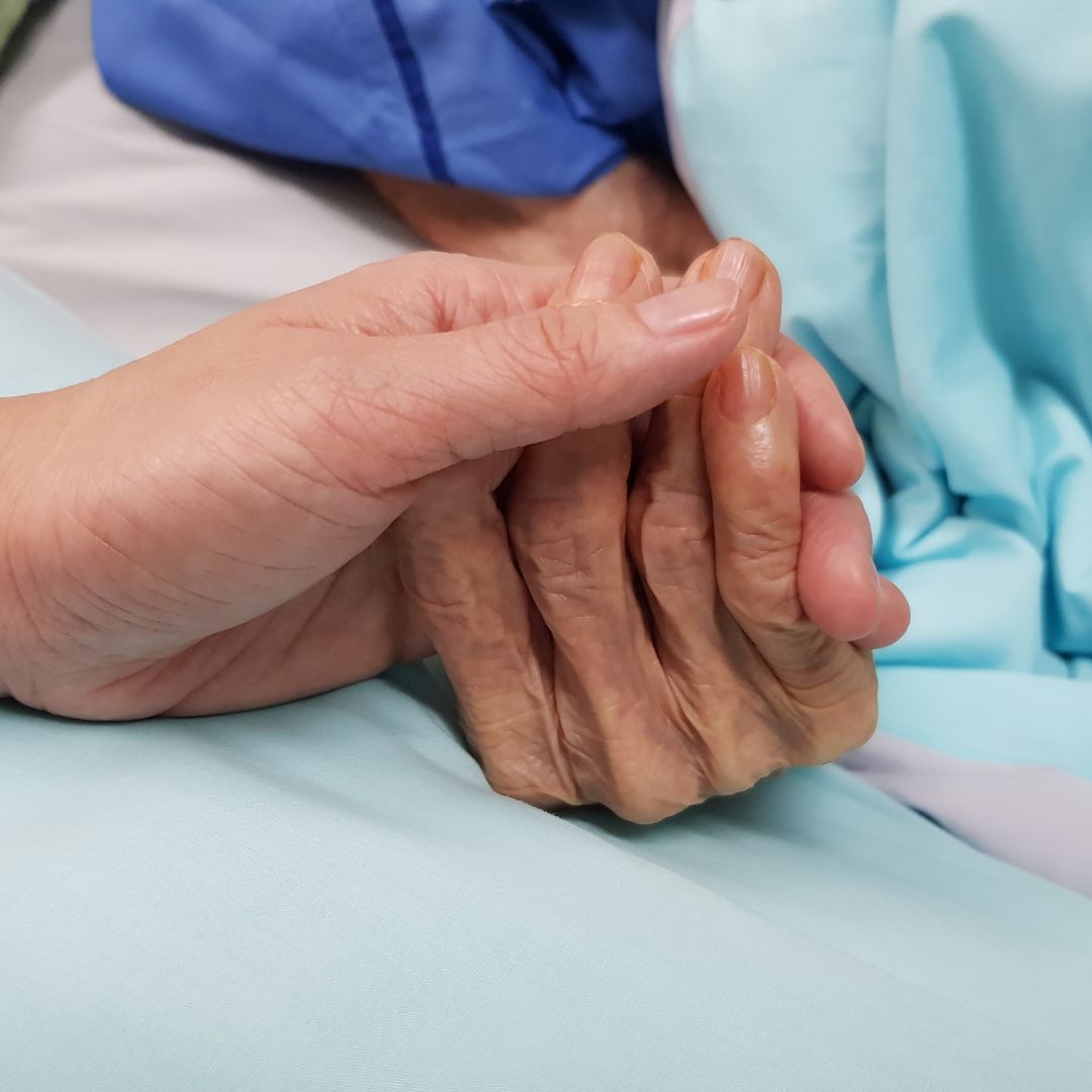 Younger person holding the hand of an older person