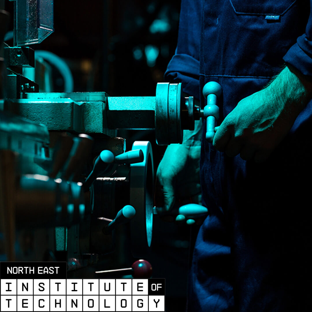 A person using a hand crank on a machine and the North East Insititue of Technlology logo in the corner.