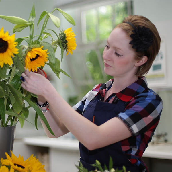 A young woman assorting a sunflower bouquet.