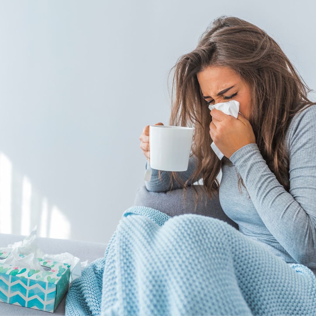 Woman in blanket sneezing into tissue