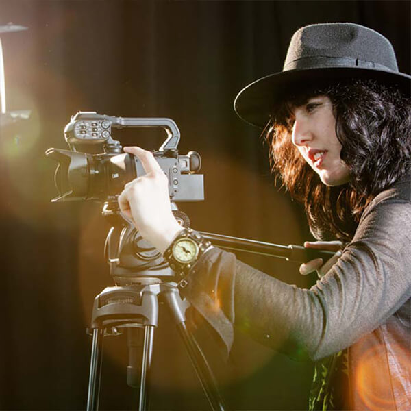 Young woman working with a camera on a stand.