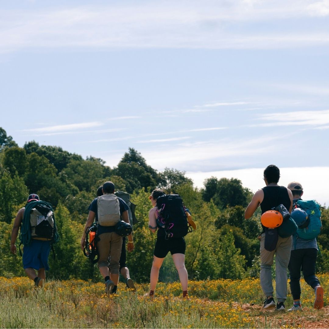 Group of people walking outside wearing large backpacks