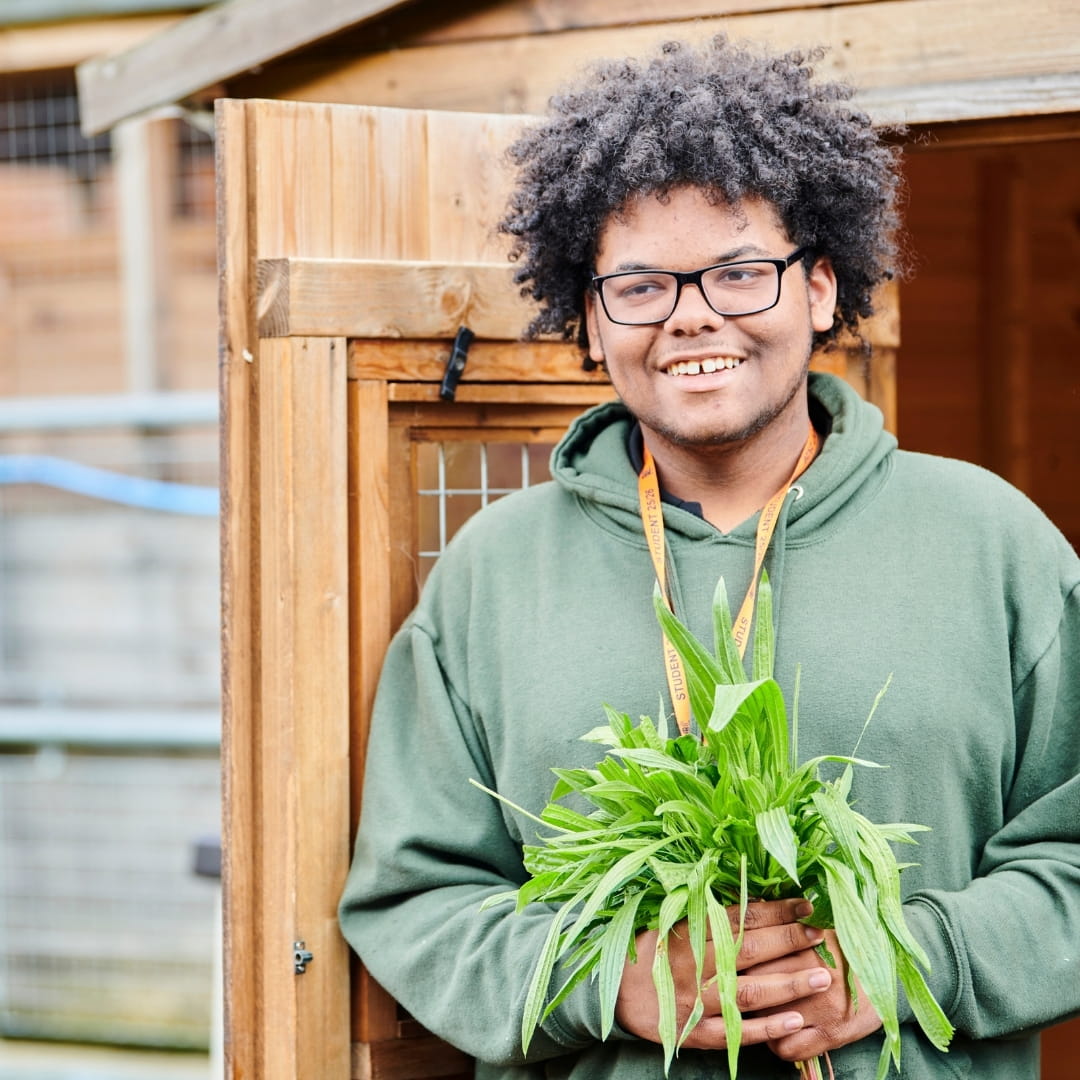 Student smiling while holding potted plant