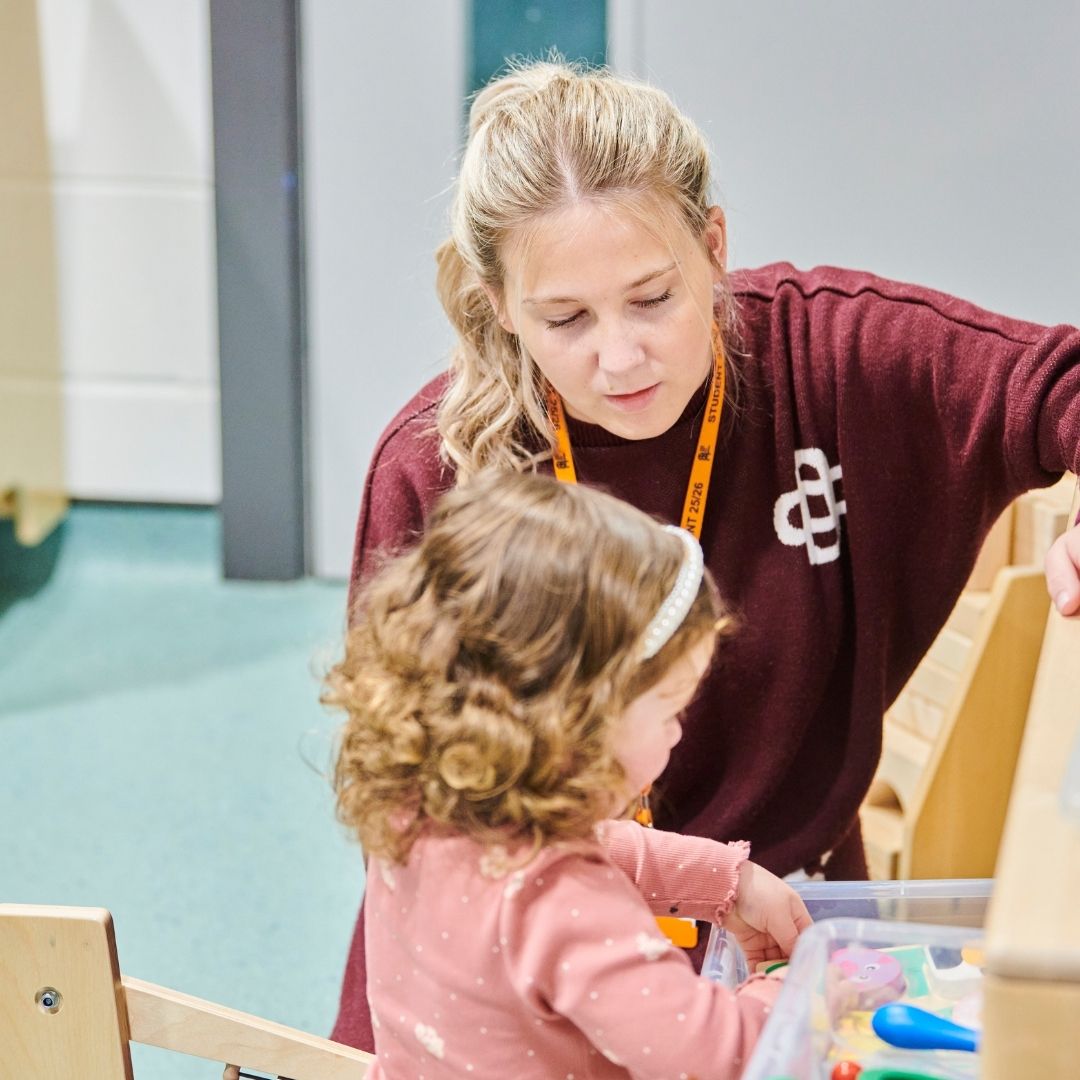 Childcare student playing with small child