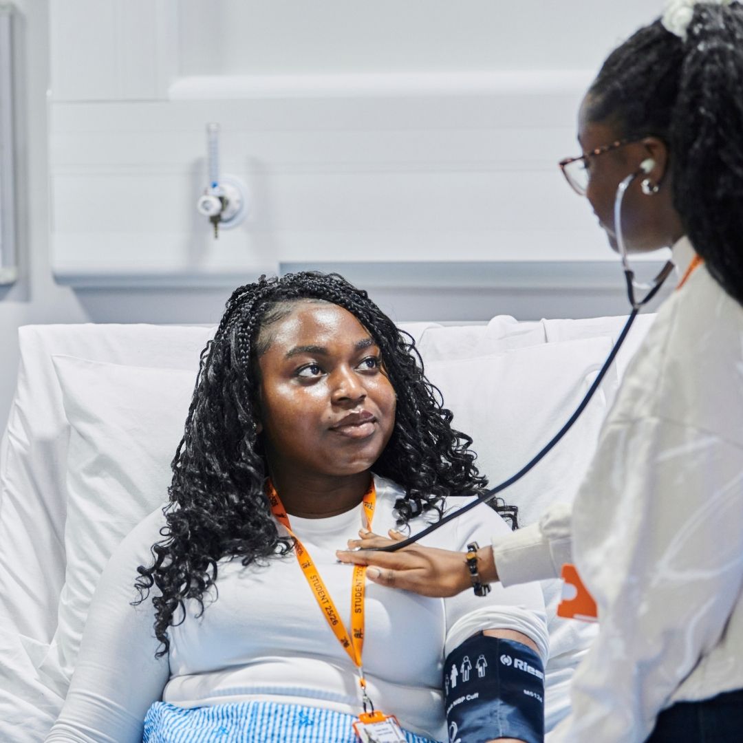 Two young students in the hospital ward classroom, practising using the harness.