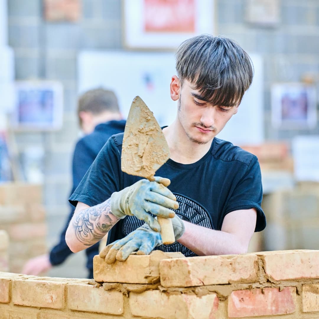 Brickwork student laying brick onto wall