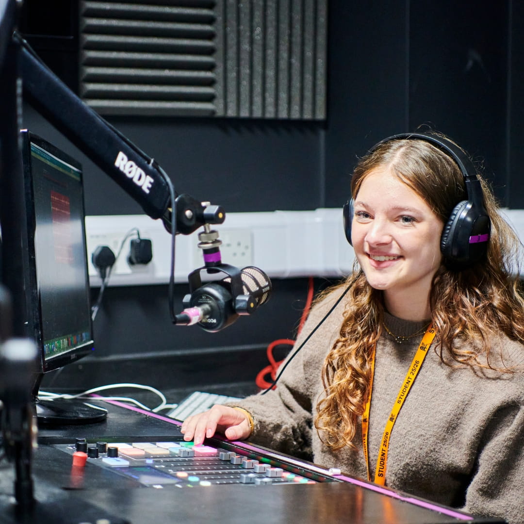 Media student wearing headphones sitting in radio studio