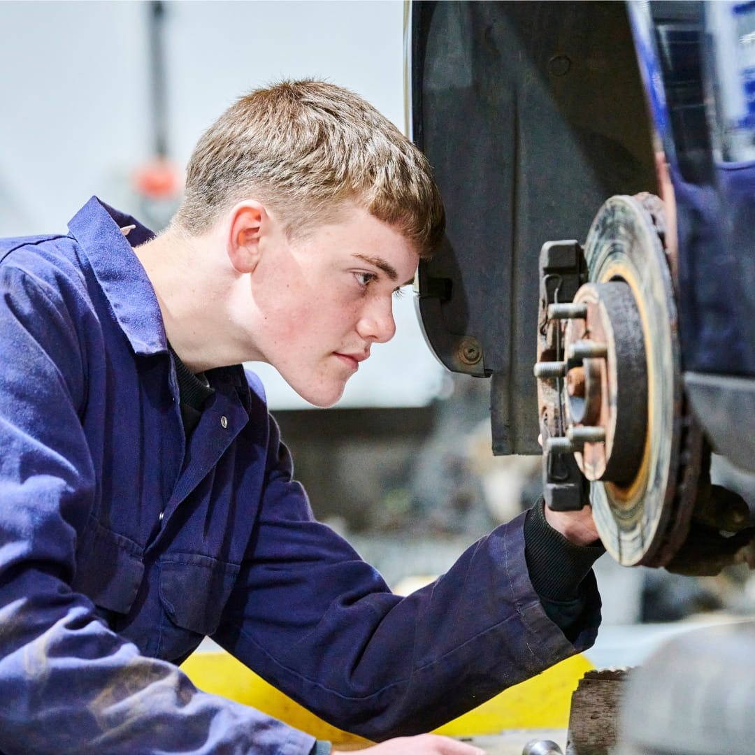 Student inspecting car wheel