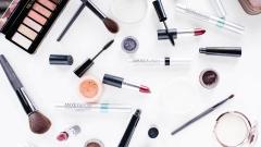 Lots of makeup products and brushes on a table 