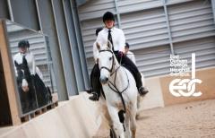 Student riding white horse next to mirror with the East Durham College Houghall Campus logo to her left