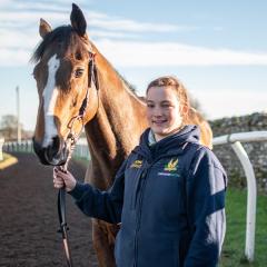 Former student Jennifer Lavelle stood next to a horse, holding the reins