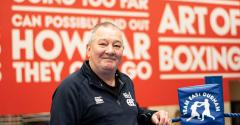 David Binns boxing coach standing in front of red wall with inspirational quotes