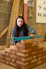 Girl holding spirit level on brick wall