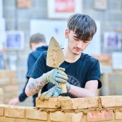 Brickwork student laying brick onto wall