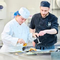 Catering student and lecturer plating up food