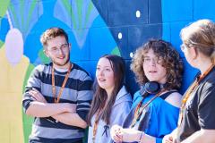 Group of students standing against painted wall chatting