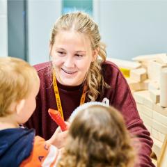 Childcare student smiling at young child