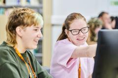 Two students smiling as one points at computer screen